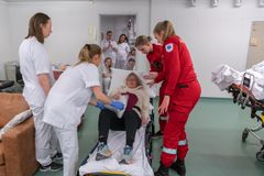 Person i sykehuskorridor blir hjulpet av medisinsk personale på en båre.