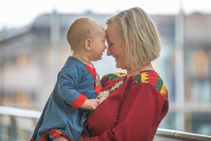 Samisk mor som holder et barn, begge har kofte.