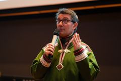 Mann i grønn samekofte taler i mikrofon.