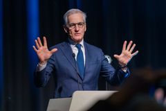 En mann i dress holder en tale ved en talerstol.