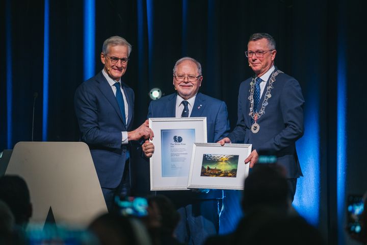 tre personer står på en scene med diplom.