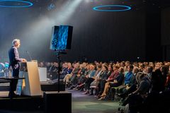 en mann taler til en stor forsamling på en konferanse.