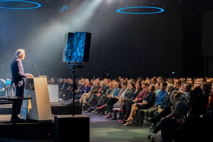 en%20mann%20taler%20til%20en%20stor%20forsamling%20p%E5%20en%20konferanse.