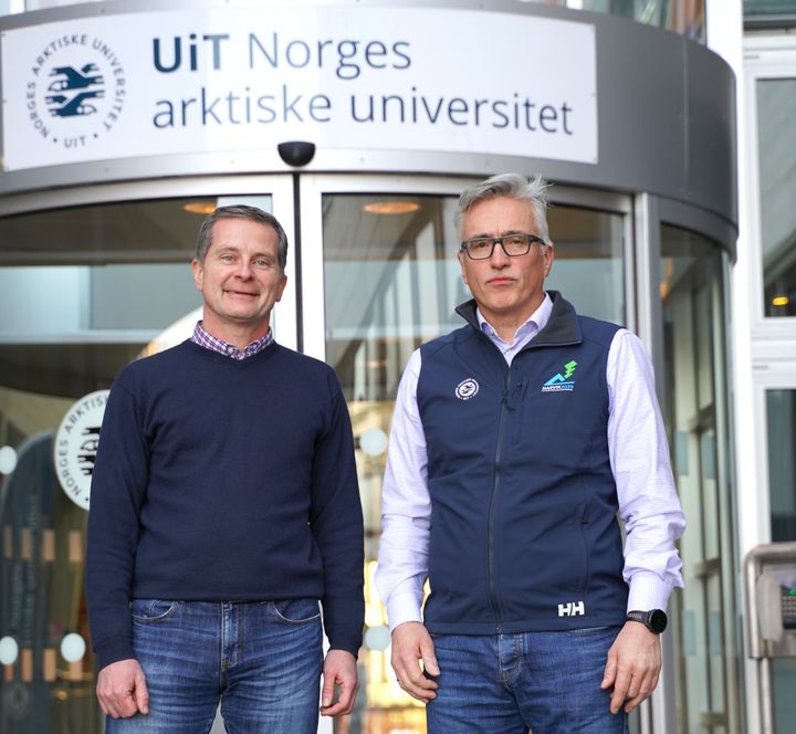 Bildet viser to menn som står foran en inngang med et skilt for UiT Norges arktiske universitet.