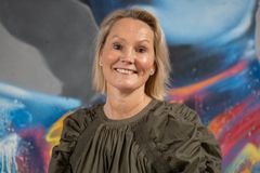 Profilbilde av kvinne som smiler, foran en farerik bakgrunn.