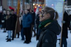 Profilbilde av kvinne med kjønnsikon malt på kinnet, står ute i en forsamling.