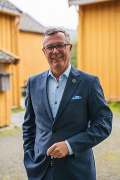 mann med dress foran gule hus