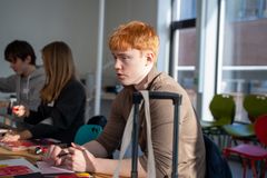 Ung gutt sitter ved bord med maling foran seg