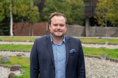 mann med dress som står ute foran universitetsbygg