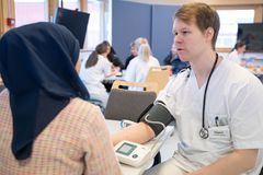 Mannleg helsefagarbeidar måler blodtrykket til ei kvinne.