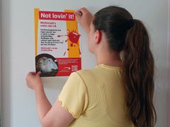 En person henger opp en kritisk plakat om McDonald's.
