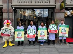 Dyrevenner utkledd som matkontrollører i hvite laboratoriefrakker som holder protestskilt mot McDonald’s salg av turbokylling.