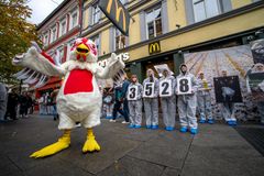 Frivillige i vernedrakter står foran en McDonald's-restaurant og holder skilter som tilsammen danner tallet 3528, mens en person iført kyllingkostyme står foran dem.