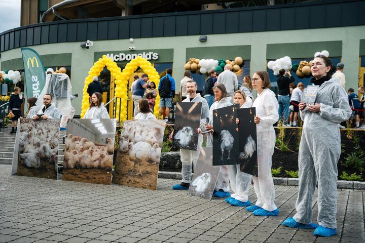 En gruppe mennesker kledd i hvite dresser holder plakater av kyllinger utenfor McDonald's ved Nadderud Fotballstadion.