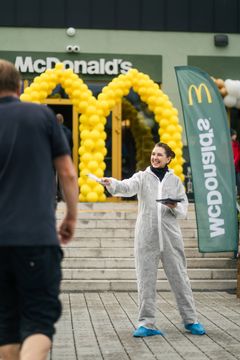 Person i smitteverndrakt står utenfor McDonald's ved Nadderud Fotballstadion.