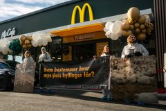 Dyrevenner i smitteverndrakter protesterer utenfor McDonald's' nye restaurant i Hønefoss, kjedens restaurant nummer 100.