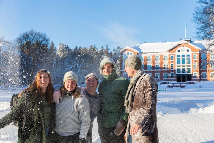 Fem glade studenter står foran Urbygningen i mye snø en januardag.