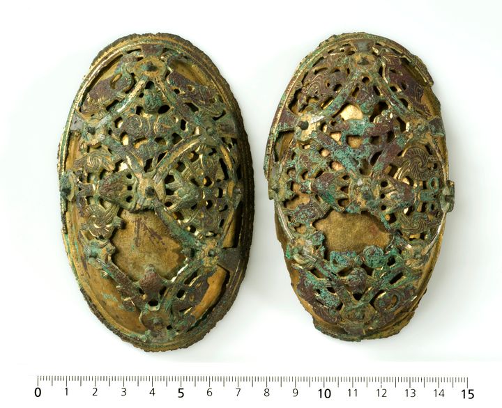 Et par draktspenner i forgylt sølv funnet i graven til vikingkvinnen fra Gausel. Deler av de rundt 40 spektakulære funnene er nå mulig å se på Arkeologisk museum ved Universitetet i Stavanger. Foto: Svein Skare, Unimusportalen