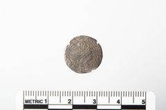 4 a. På gjenstandens bakside kan man tydelig se kobberplaten som er lagt på, og hvordan myntens kant er foldet rundt kanten av platen.