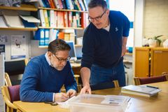 Arkeolog Sigmund Oehrl fra Arkeologisk museum, Universitetet i Stavanger og arkeolog Lars Søgaard Sørensen fra Rogaland fylkeskommune ser på inngraveringen på gullbiten.