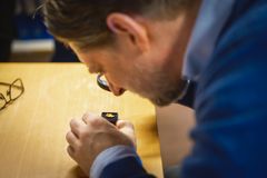 Professor i arkeologi, Sigmund Oehrl, undersøker den nyinnkomne gullgubben med forstørrelsesglass.