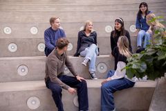 En gruppe unge mennesker sitter i en trapp og prater