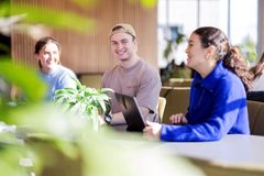 Tre unge mennesker samarbeider rundt et bord
