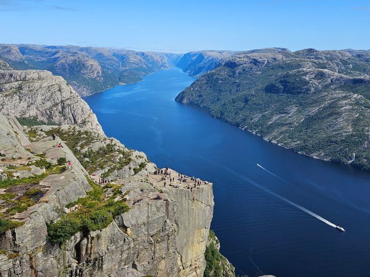 Utsikt mot fjellet Preikestolen. Mange besøkende på toppen. Foto.