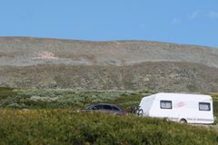Bil med campingvogn med villreinflokk i bakgrunnen på Grimsdalsveien i Rondane.