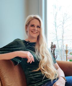 Portrett av Lene Åm Røskaft sittende i en brun lenestol ved et vindu.
