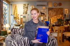 Thea Karinen i Balthazar Interior holder opp en blå coffee table-bok i en møbelbutikk.