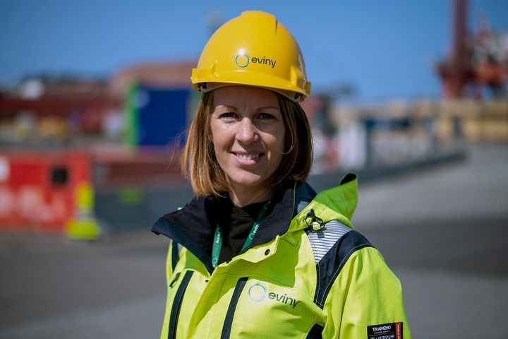 Dame med hjelm og gul uniform på et industriområde