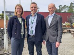 Tre personer står utendørs og smiler mot kameraet.