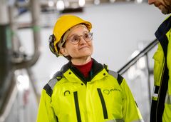 Kvinne med gul hjelm og vernetøy står inne i et kraftverk.