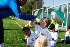 Et barn og en voksen gir en high five til hverandre på en fotballbane