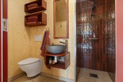 Røde fliser, naturmaterialer og enkle detaljer gir badet i tilbygget et særpreget uttrykk.