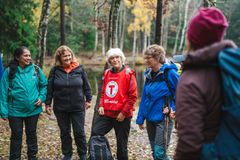 En gruppe mennesker som står og snakker i en skogkledd park.