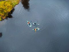 Tre personer padler i packraft på en innsjø.