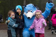 Tre barn med ansiktsmaling står sammen med en person i et blått revekostyme under en utedag i regi av DNT.