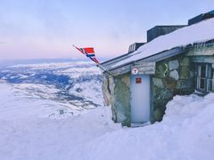 Gaustatoppen Turisthytte dekket av snø, med norsk flagg heist.