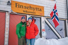 To personer foran Finsehytta med norsk flagg.