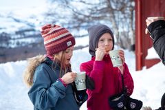 To barn drikker fra kopper ute i snødekte omgivelser ved Gjevilvasshytta i Trollheimen.