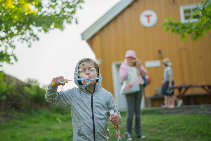 Barn leker med såpebobler foran en DNT-hytte