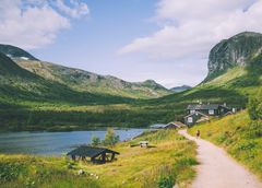 Utsikt over Gjendebu med fjell, vann og hytter i vakker natur.