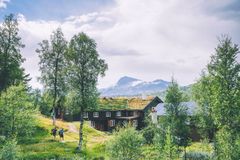 Utsikt over Trollheimshytta omgitt av trær og fjell i bakgrunnen.