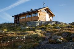 En liten hytte på en steinete ås med blå himmel i bakgrunnen.