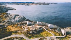Tre moderne hytter integrert i landskapet, med panoramautsikt over havet.