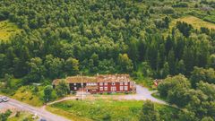 Bilde av Gjevilvasshytta omgitt av frodig skoglandskap i Trollheimen.