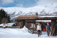 To personer går ut fra tunet på en betjent DNT-hytte