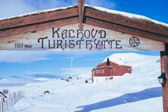 Veiskilt ved Kalhovd Turisthytte, med snødekt landskap i bakgrunnen.